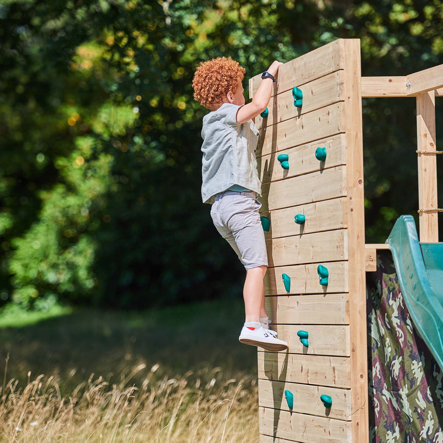 A boy climbing the rock wall in Plum Play's Wooden Climbing Cube
