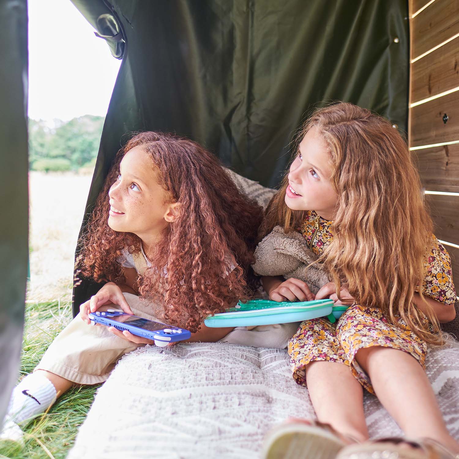 Two girls sitting inside the secret play den area of Plum Play's Wooden Climbing Cube