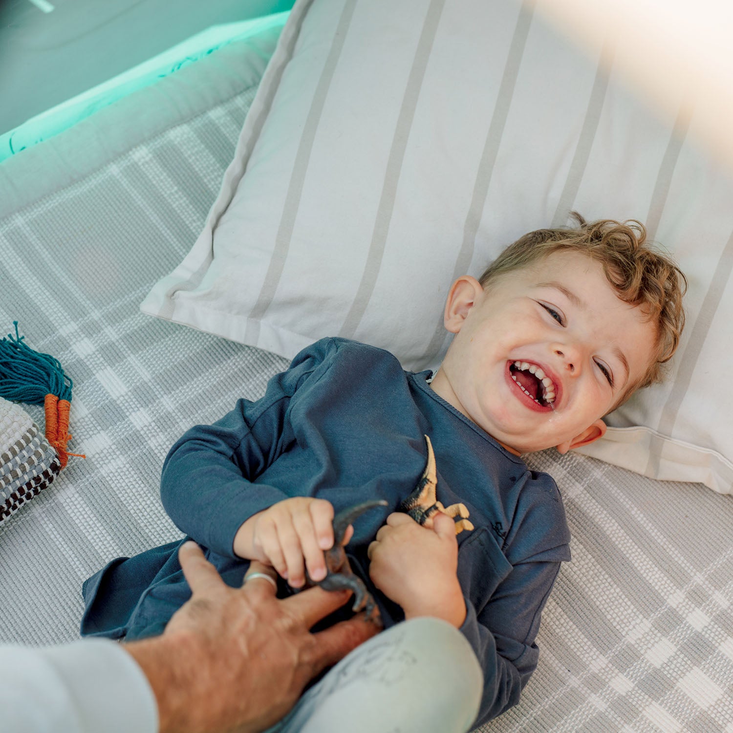 A young boy laughing while lying on  Plum's My First Wooden Playcentre secret den