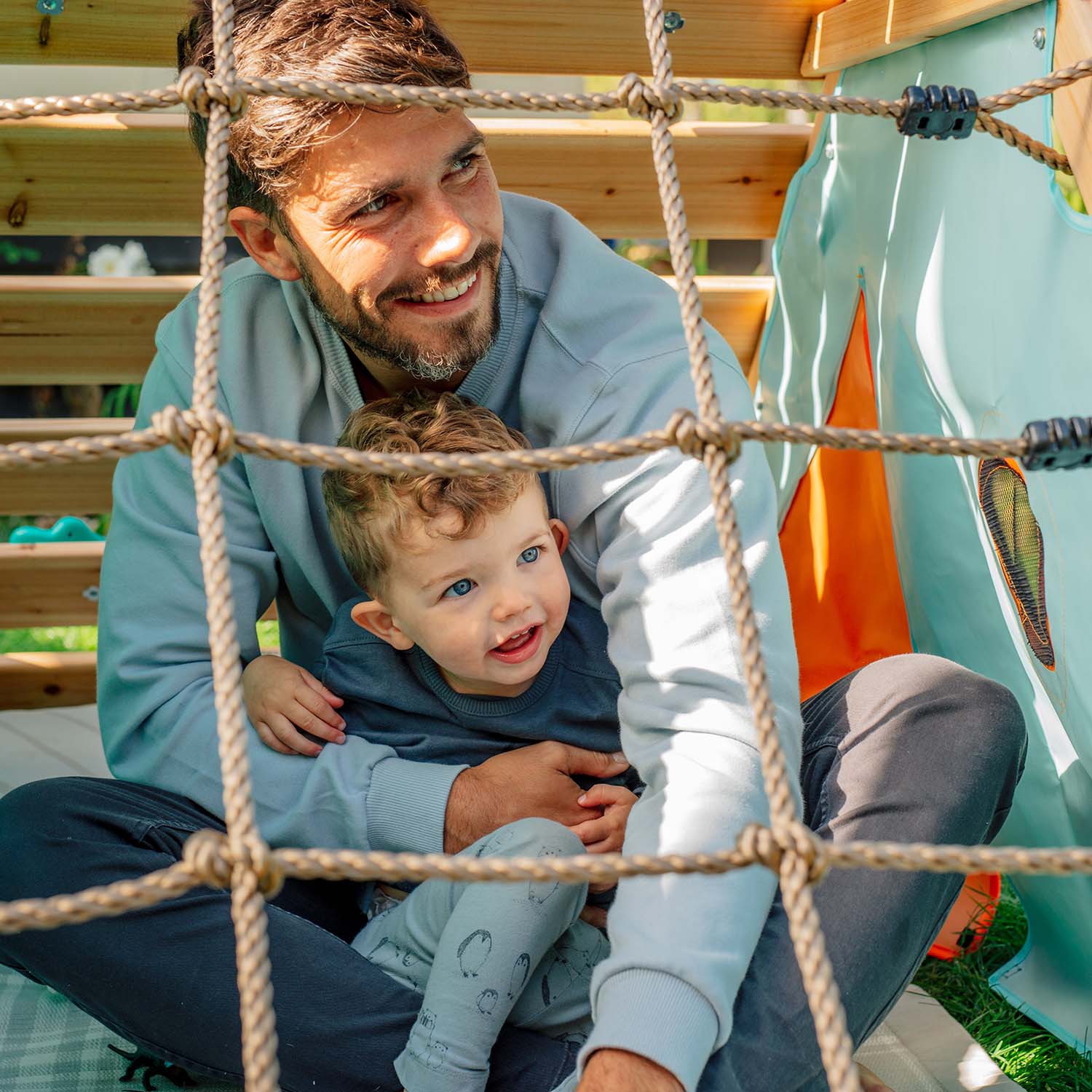 Dad and son sitting in the den of Plum Play's My First Wooden Playcentre