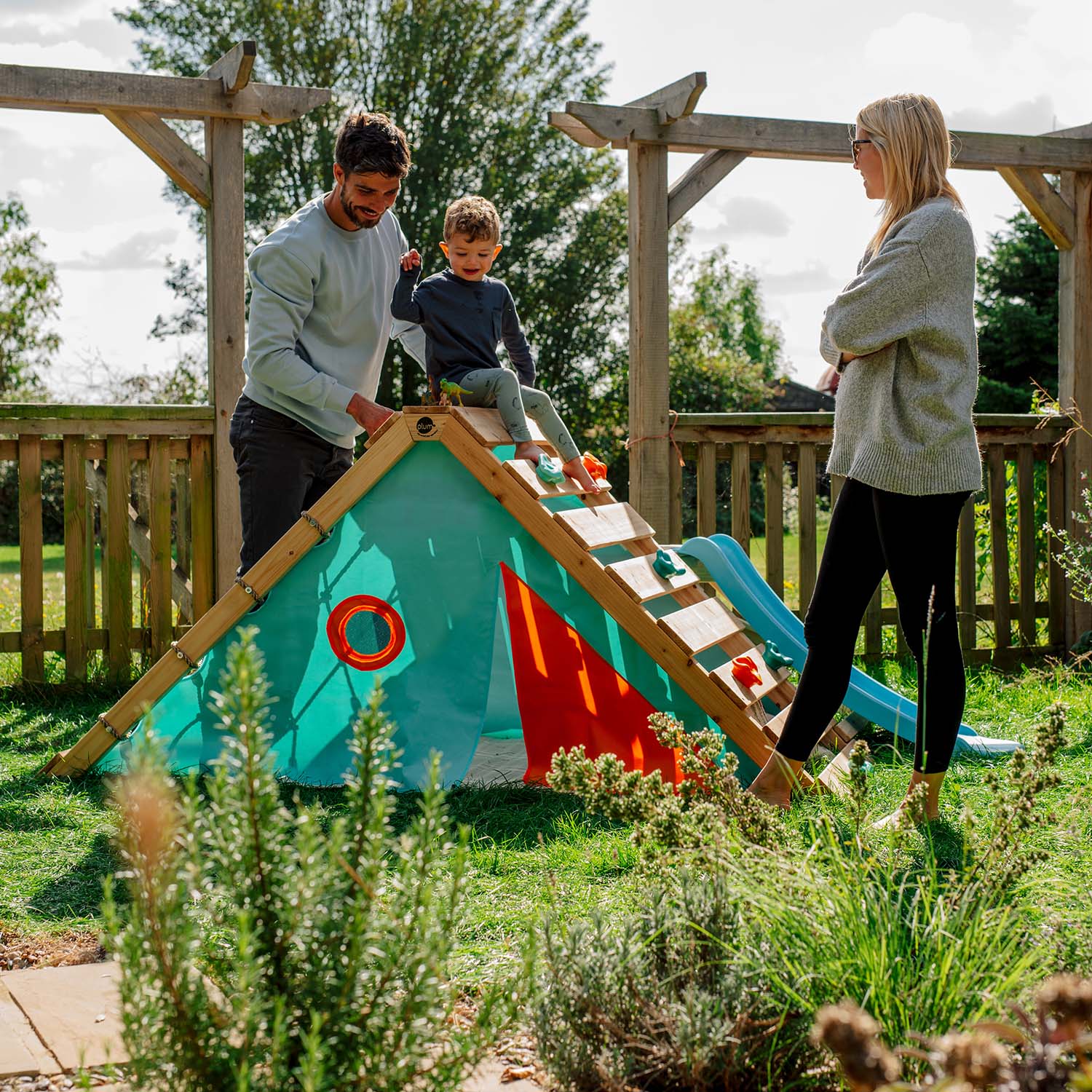 Mom, dad and child playing and hanging out in the garden with Plum Play's My First Wooden Playcentre