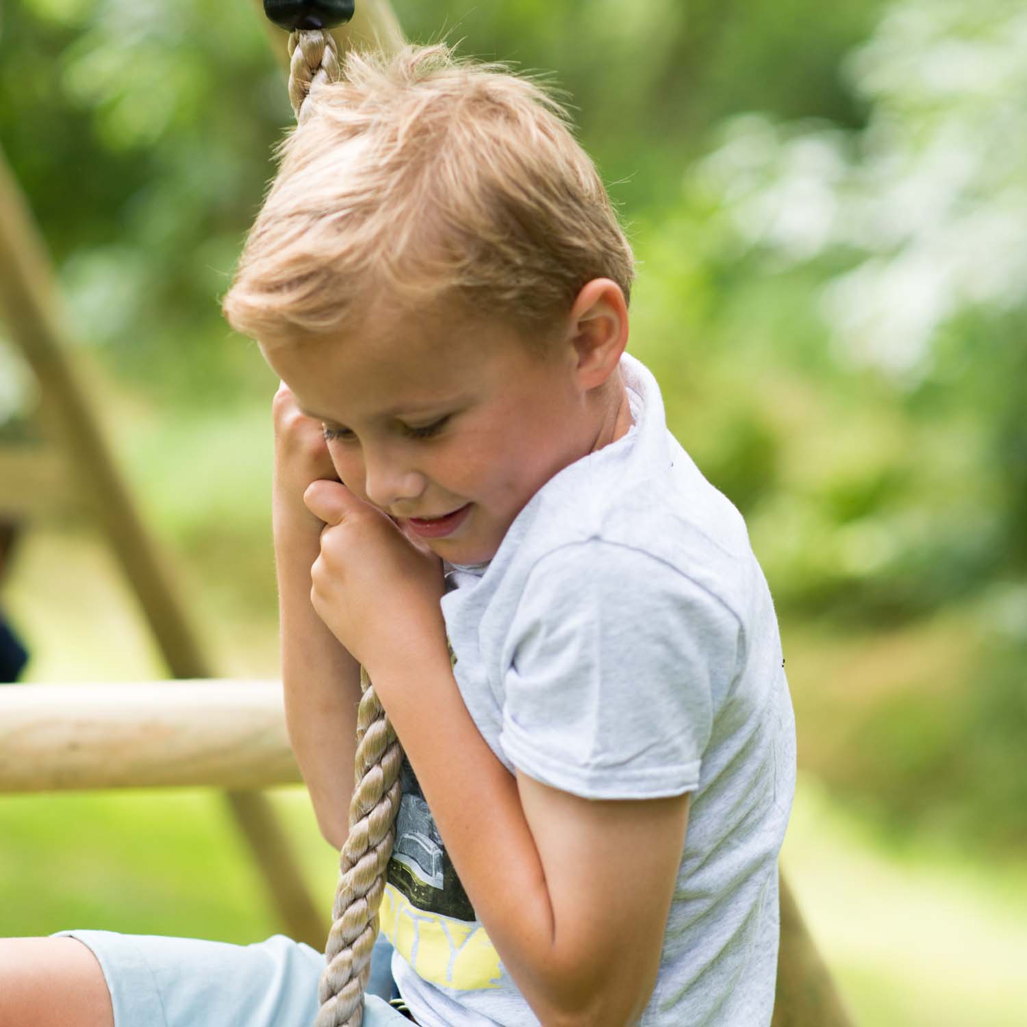Boy hanging in the climbing rope of Plum Play's Giant Baboon Wooden Swing Set