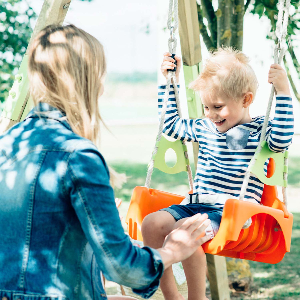 Young boy and mother having fun in Plum Play's Wooden Growing Swing Set