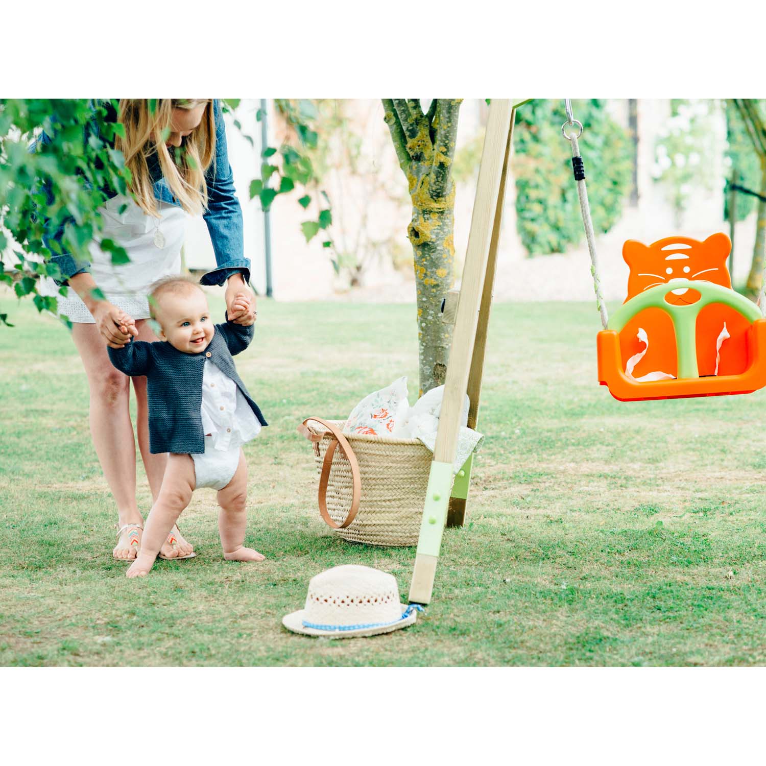 Mom assisting her baby to walk beside Plum Play's Wooden Growing Swing Set