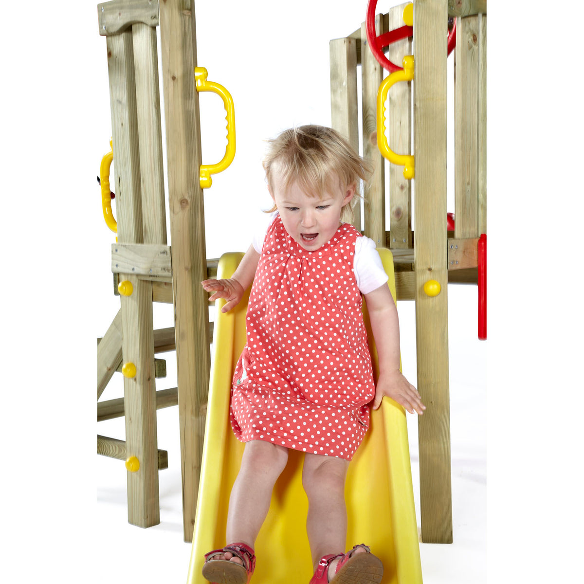 A baby girl sliding in Plum Play's Toddlers Tower Wooden Climbing Frame