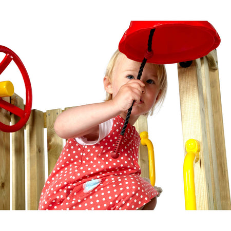 A toddler ringing the red bell accessory in Plum Play's Toddlers Tower Wooden Climbing Frame