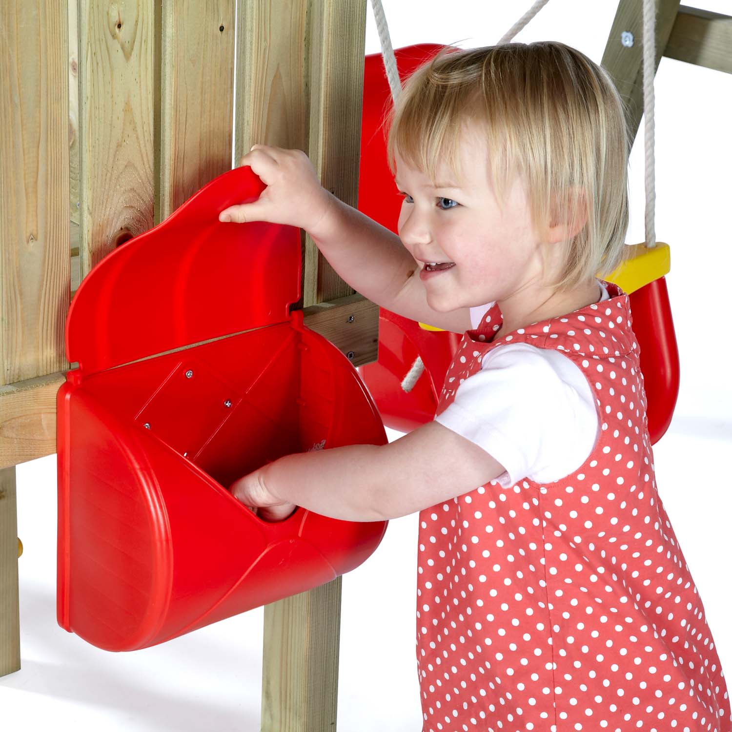 A toddler smiles as she opens the red box accessory in Plum Play's Toddlers Tower Wooden Climbing Frame