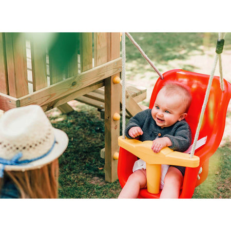An infant sitting on the baby swing of Plum Play's Toddlers Tower Climbing Frame while smiling to her mother