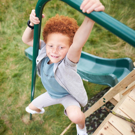 Boy sliding down using the 2.5 metre fireman's pole in Plum Play's Wooden Climbing Cube XL