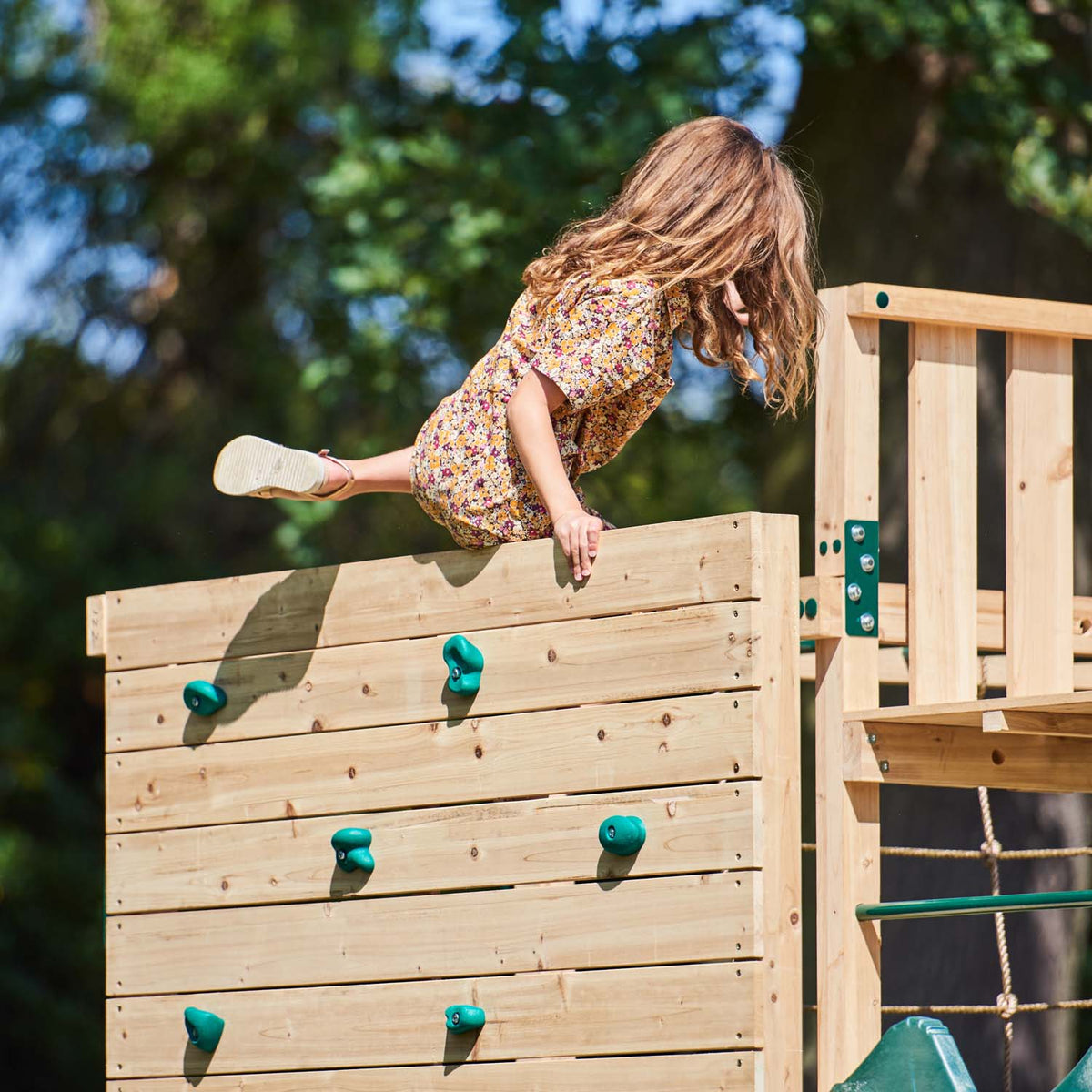 Girl climbing using the rock wall in Plum Play's Wooden Climbing Cube XL