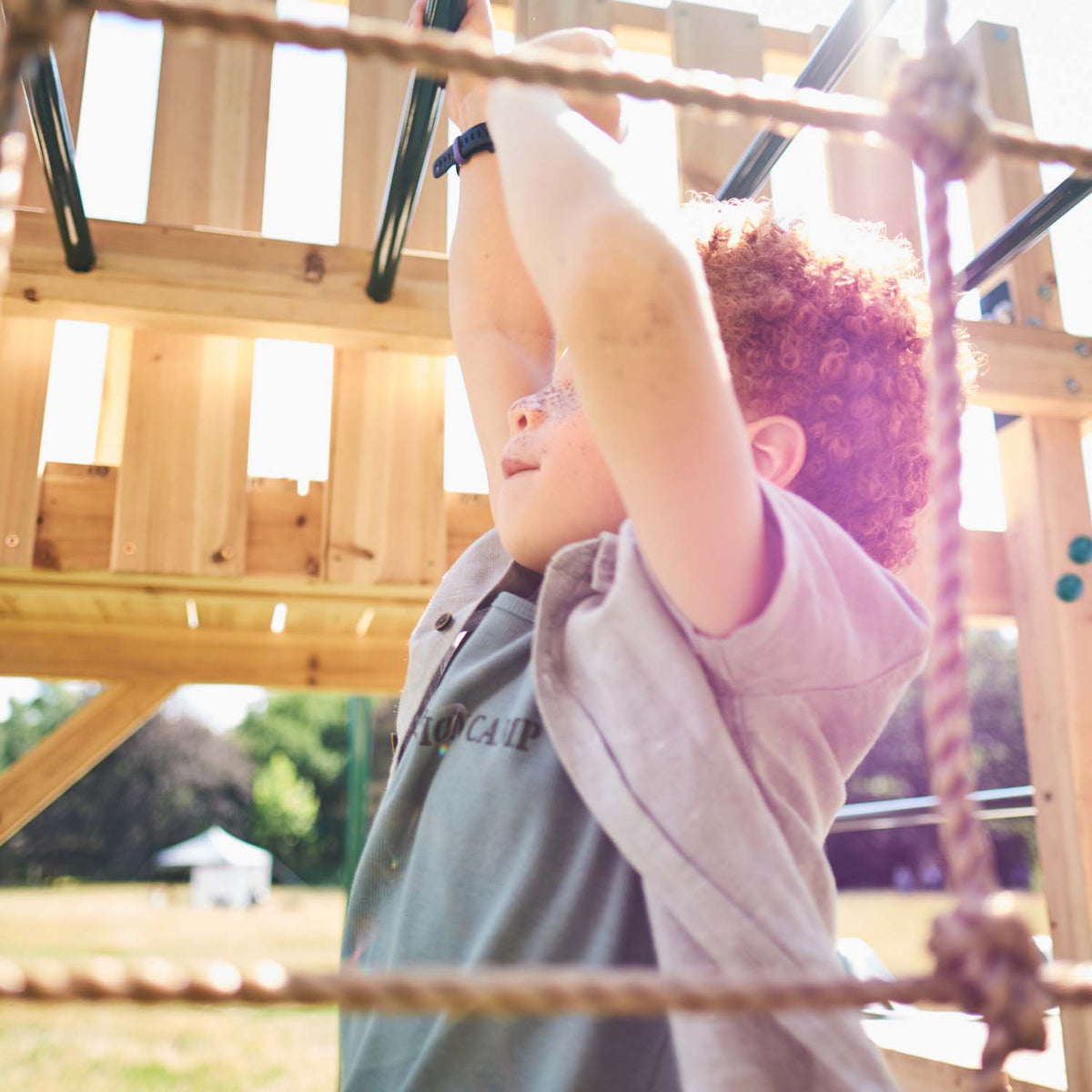 Boy playing in the monkey bars in Plum Play's Wooden Climbing Cube XL