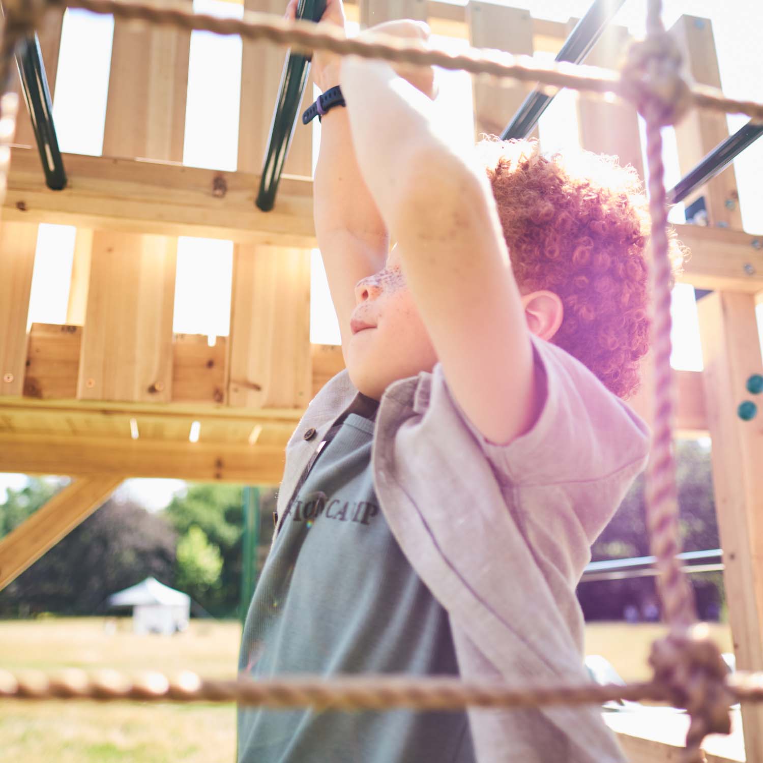 Boy playing in the monkey bars in Plum Play's Wooden Climbing Cube XL
