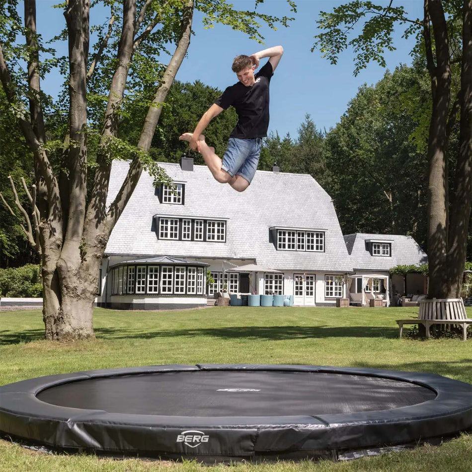 young man jumping on BERG SPORTS Elite InGround Round Trampoline