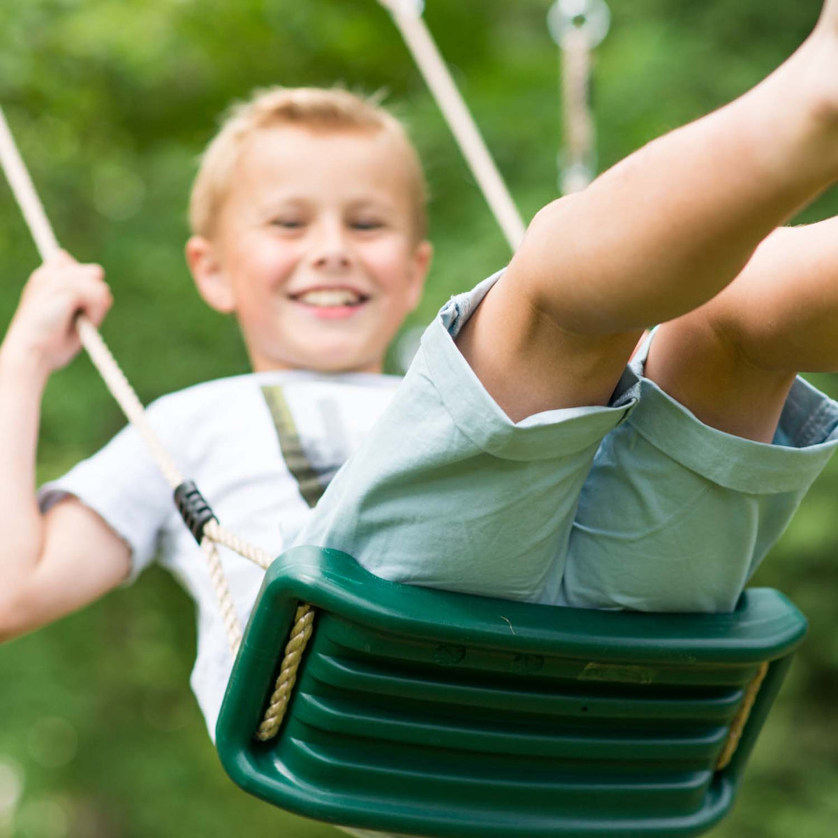 Boy swinging in Plum Play's Gibbon Wooden Swing Set