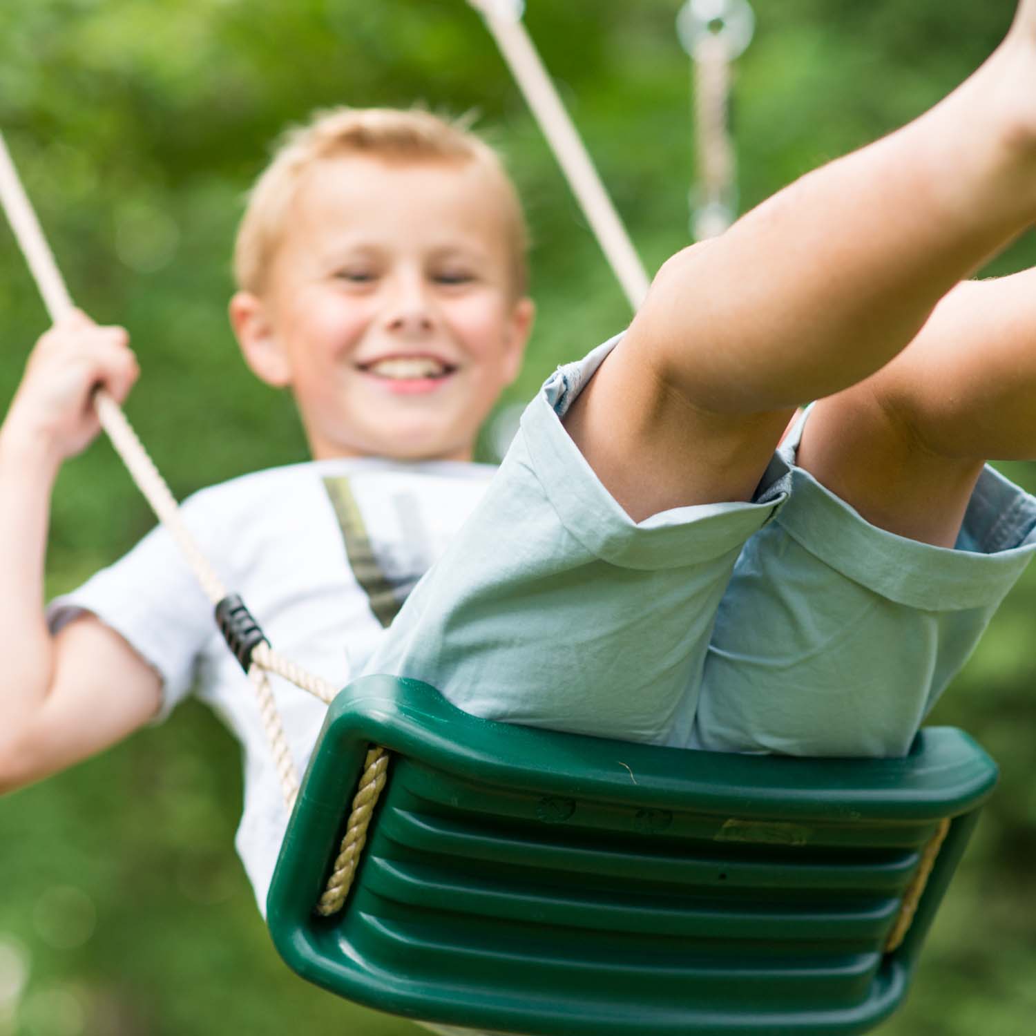 Boy swinging in Plum Play's Gibbon Wooden Swing Set