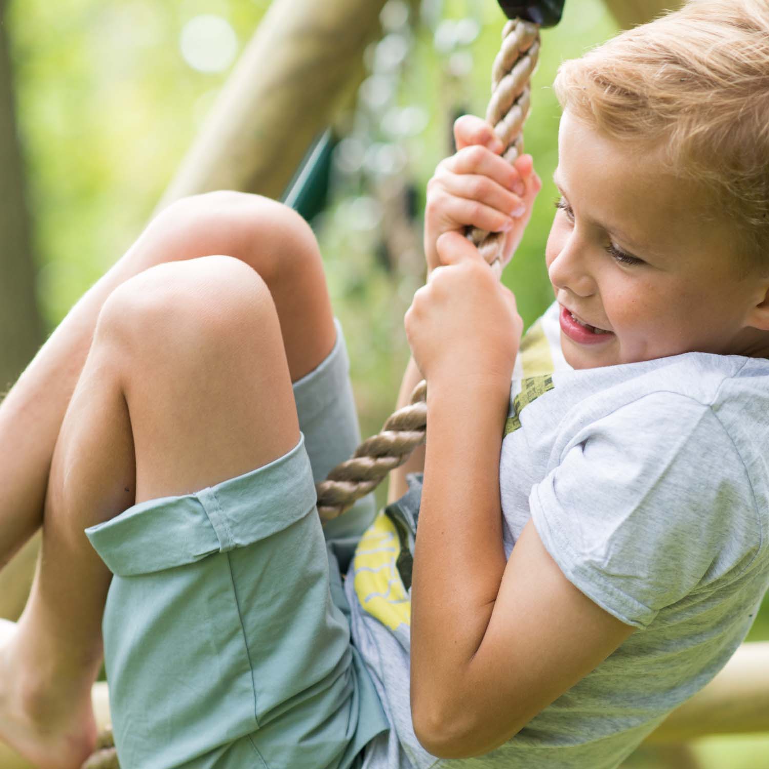 Boy climbing in Plum Play's Gibbon Wooden Swing Set