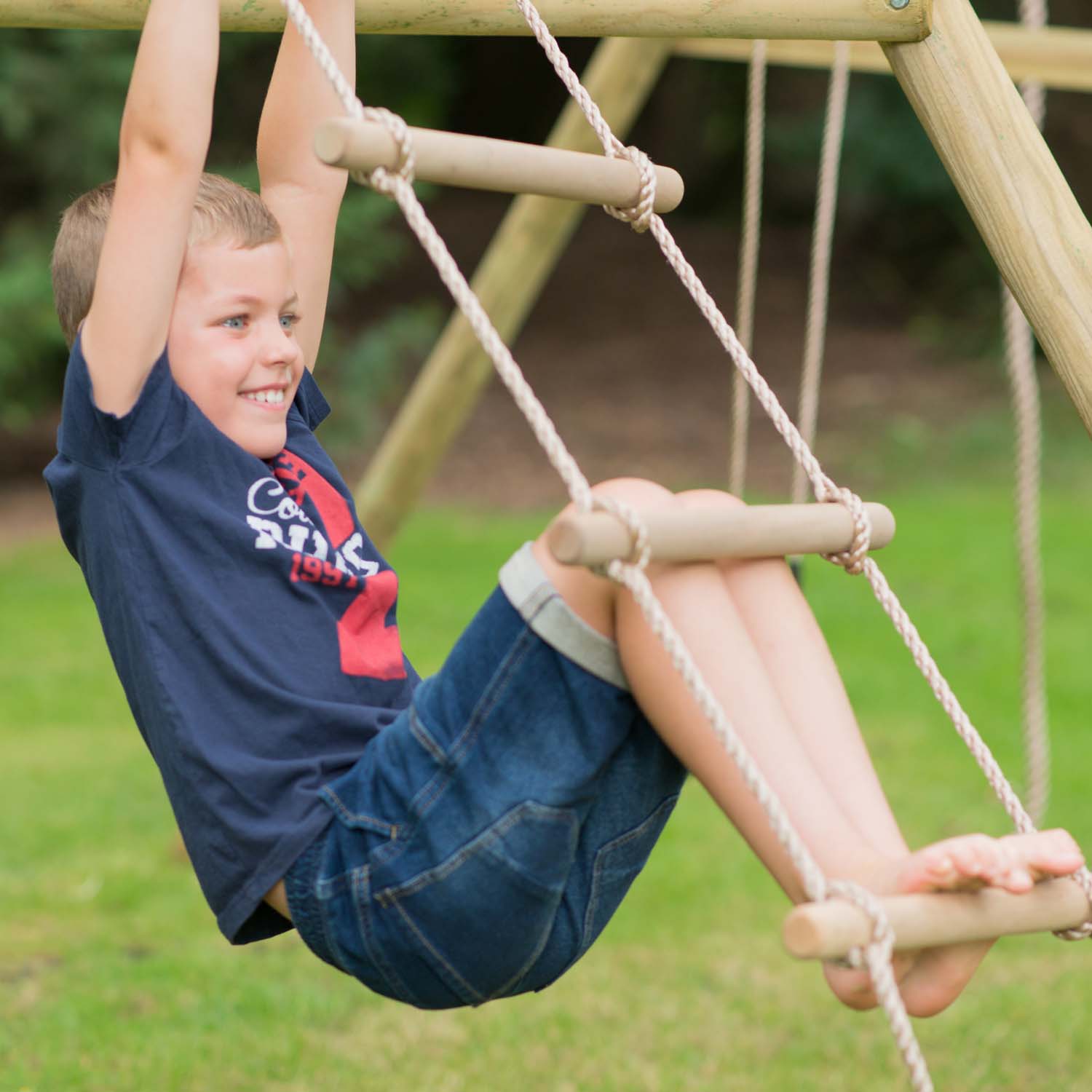 Boy climbing the rope ladder in Plum Play's Gibbon Wooden Swing Set
