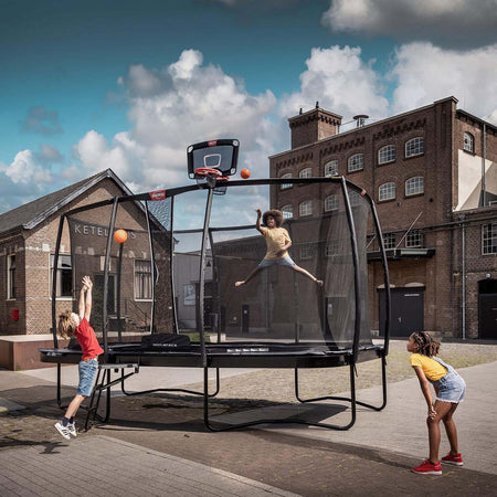 three children playing baskeball on a BERG trampoline with attached BERG Basketball TwinHoop accessory