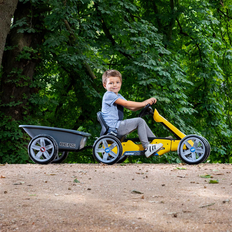 Boy riding a BERG Reppy with BERG Trailer Medium accessory attached