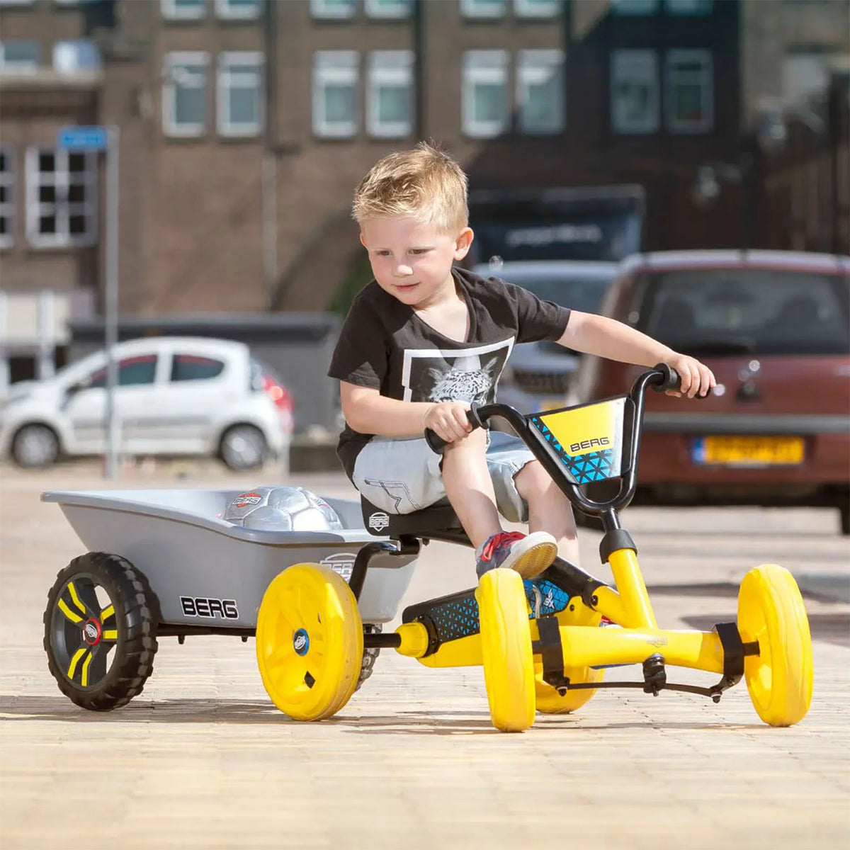 Young boy riding a BERG Buzzy Go-Kart with attached BERG Trailer Small in Grey colour