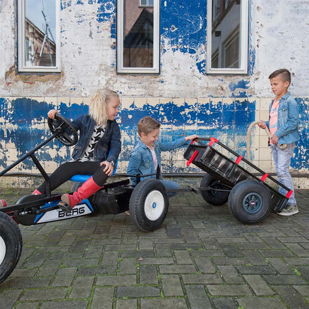 Children playing with a BERG Go-Kart with attached BERG Trailer XL accessory