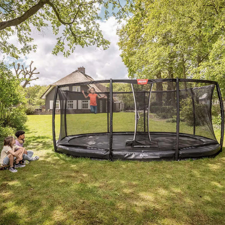 three children playing in BERG Grand Elite InGround Oval Trampoline with Safety Net Deluxe