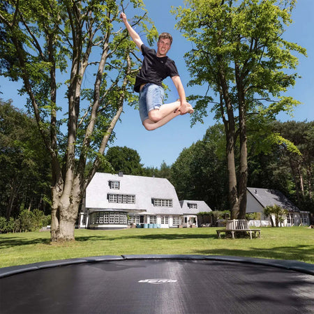 a young man playing on BERG SPORTS Elite InGround Round Trampoline