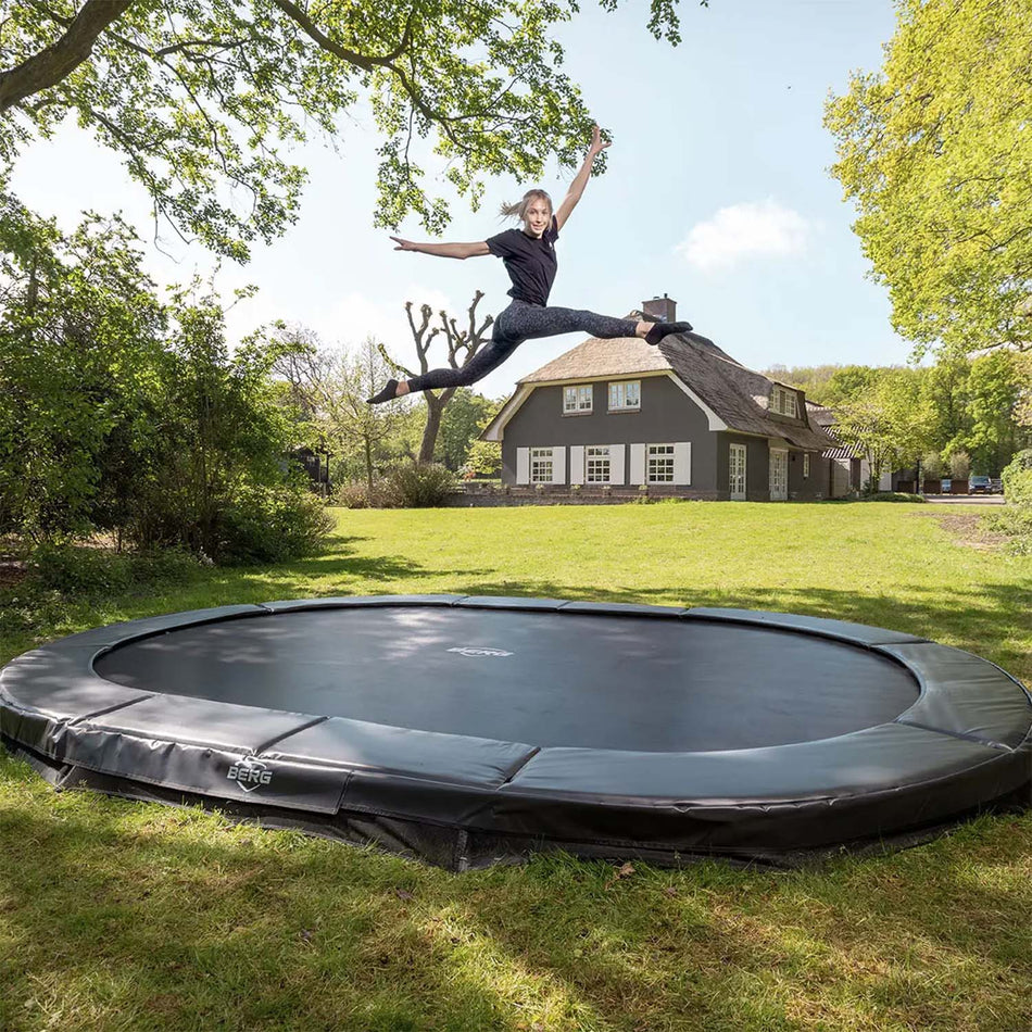 young woman performing acrobatics while bouncing on BERG SPORTS Grand Elite InGround Oval Trampoline 