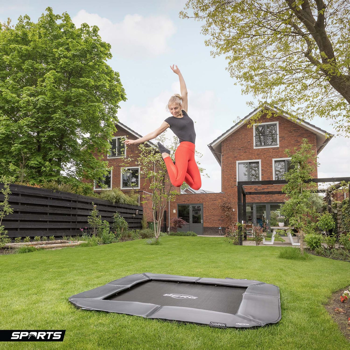 a young woman bouncing on a BERG SPORTS Ultim Champion FlatGround Square Trampoline