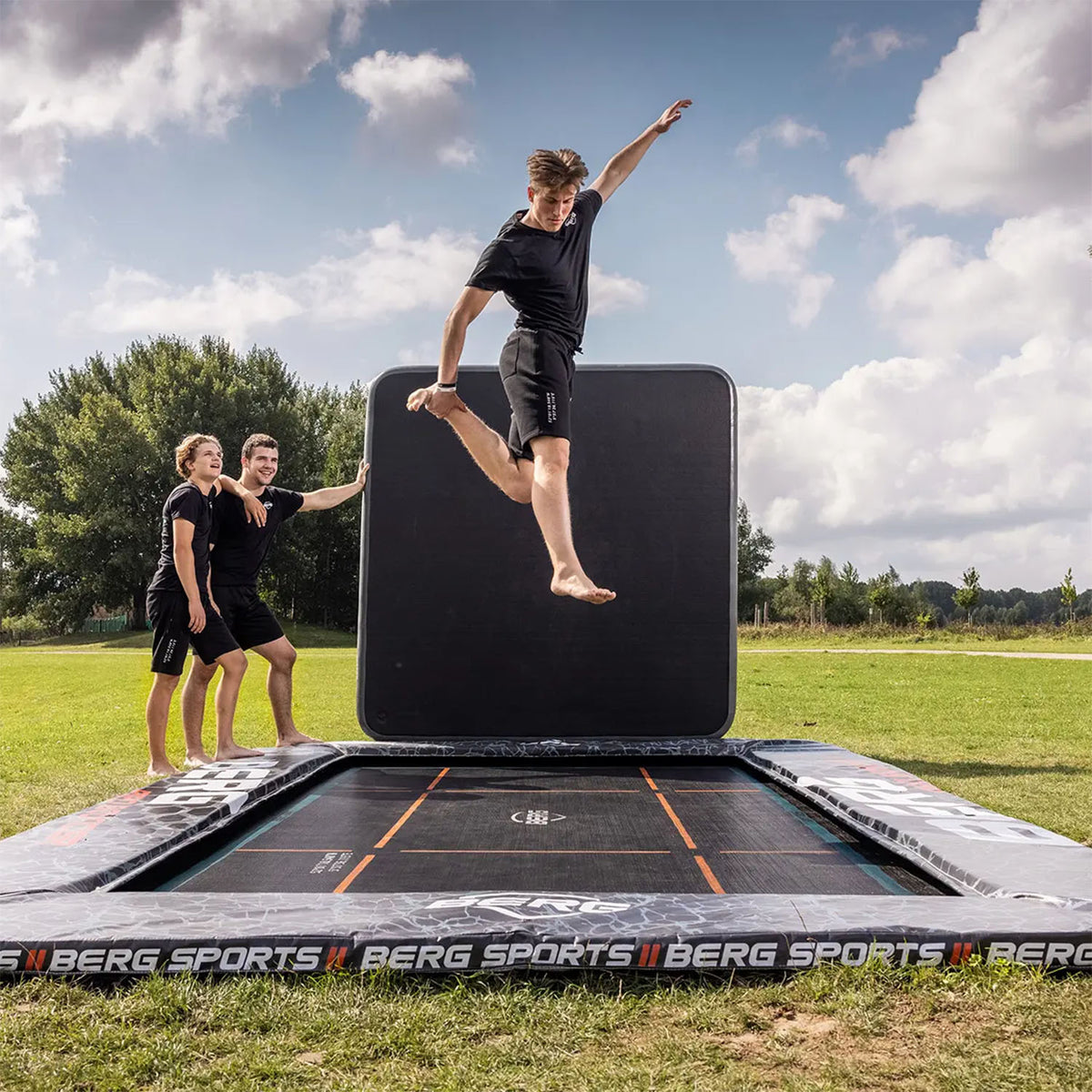 trained athlete performing acrobatics on a BERG SPORTS Ultim Pro Bouncer FlatGround Rectangular Trampoline with AeroWall