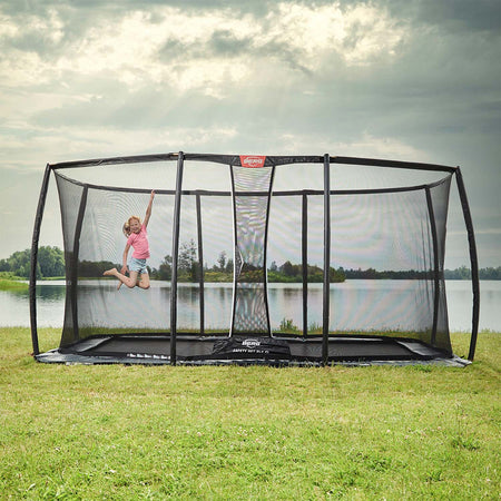 A girl playing in the BERG Ultim Champion FlatGround Rectangular Trampoline with Safety Net DLX XL