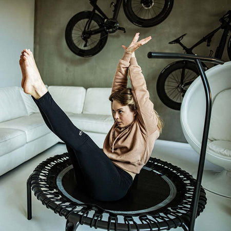 ACON FIT 1.12m Round Trampoline with Handlebar in Black finish, photographed in modern home gym setting to illustrate space-efficient fitness equipment integration.