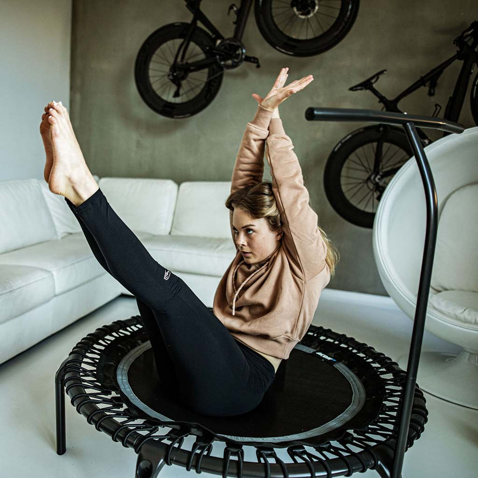 ACON FIT 1.12m Round Trampoline with Handlebar in Black finish, photographed in modern home gym setting to illustrate space-efficient fitness equipment integration.