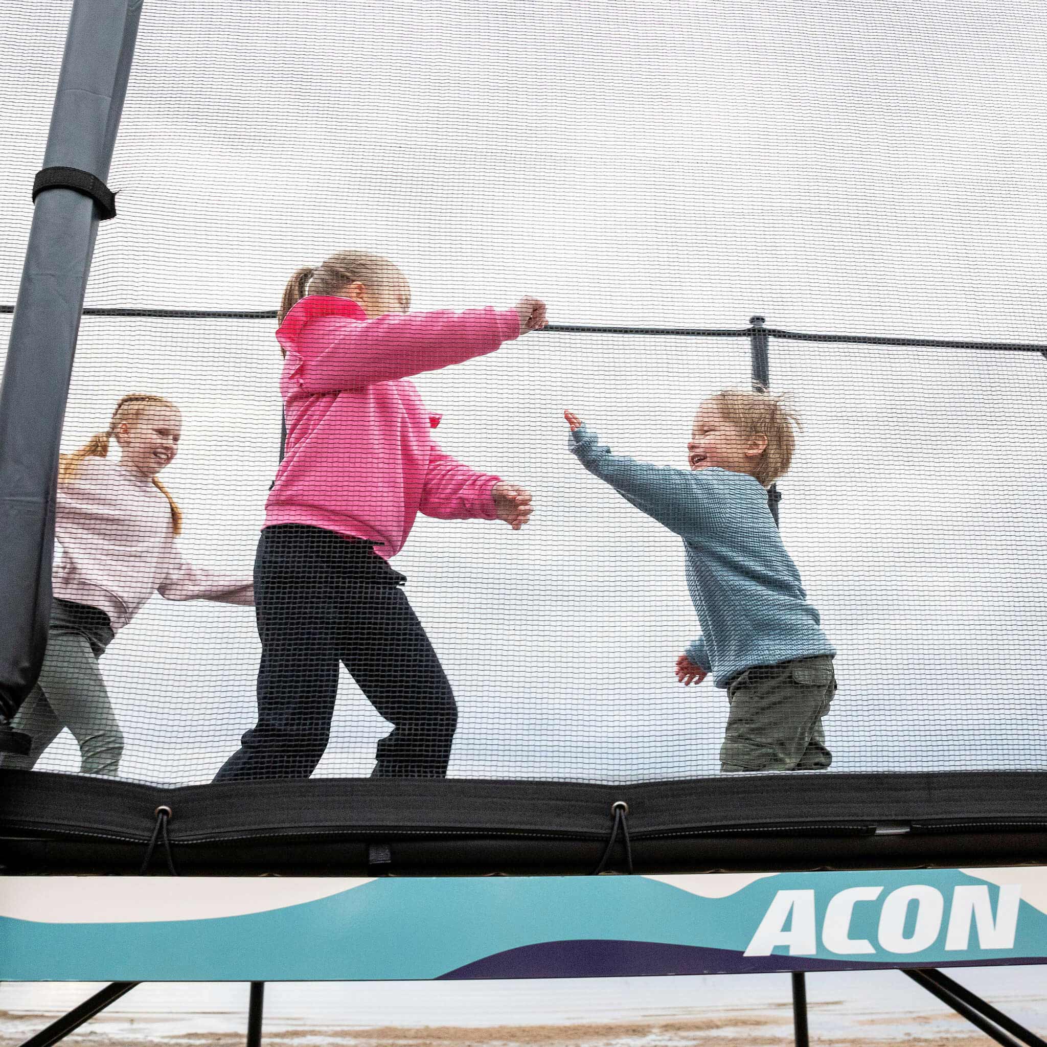 Multiple children engaged in group play activities on the Acon X Trampoline, illustrating the social benefits and shared enjoyment of quality outdoor recreation equipment.