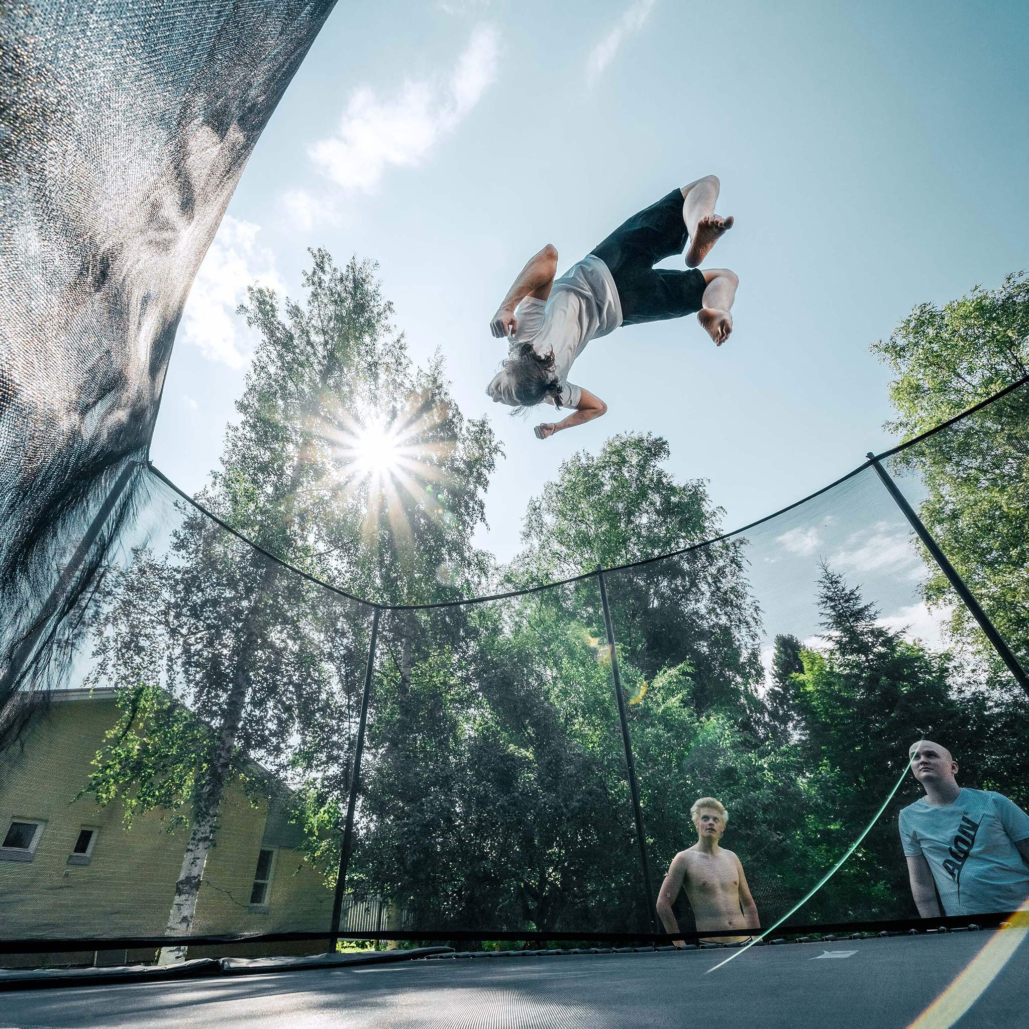 Advanced athlete performing aerial maneuvers on Acon 16 HD PRO trampoline while peers observe, demonstrating the equipment's capability for serious athletic training and skill development.