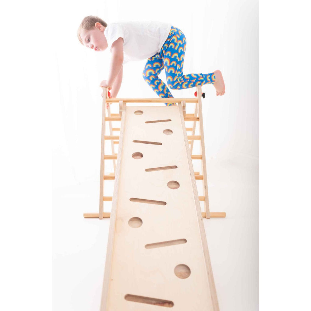 Child climbing over Pikler triangle and slide